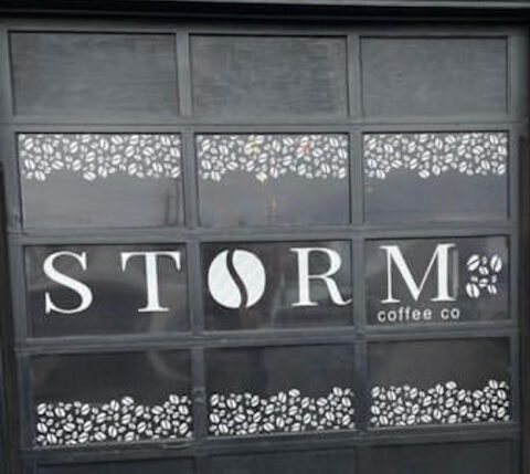 Custom window graphics on a Storm Coffee shop storefront installed by OneWorld Window Tinting 